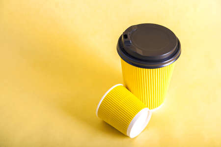 Takeaway yellow cardboard cup on yellow background close-up and copy space.の写真素材