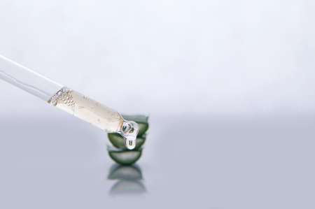 Pipette and aloe vera in serum gel with oxygen bubbles close up. Close up of dropper for cosmetics with empty space.の写真素材