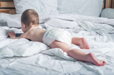 Child 1 year old on bed with mobile phone close-up.の写真素材