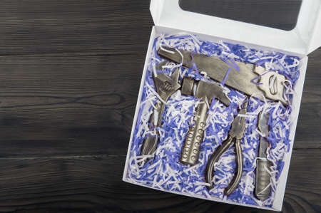 Chocolate tools in gift box on wooden background close-up and copy space. Tinsel in trendy blue.の写真素材