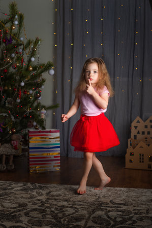 Little girl in red skirt for Chinese New Year at home dreaming of gift.の写真素材