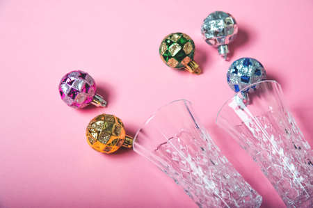Two champagne glasses and Christmas balls on pink background.の写真素材