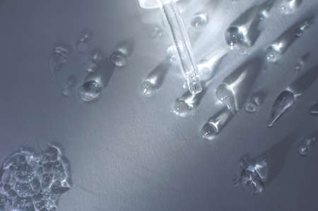 Dropper with drops on a gray background. Serum, oil or gel from natural plants as a source of skin hydration. Top view, copy space ..の写真素材