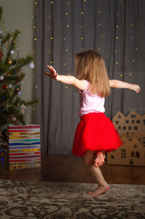 Little girl in red skirt for Chinese New Year at home dreaming of gift.の写真素材