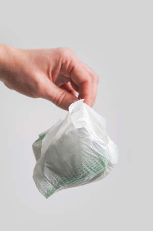 Hand holds dirty used diaper for garbage..の写真素材