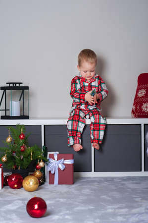 Cute toddler boy in pajamas eating christmas cookies at home close-up. New Year's comfort at home, bedroom decor.の写真素材