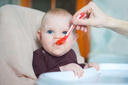 Baby 7 months old eats from spoon close-up.の写真素材
