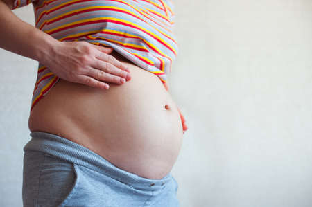 Pregnant woman touching her belly close up.