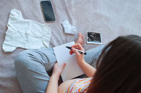 Pregnant woman writes list for maternity hospital for baby.