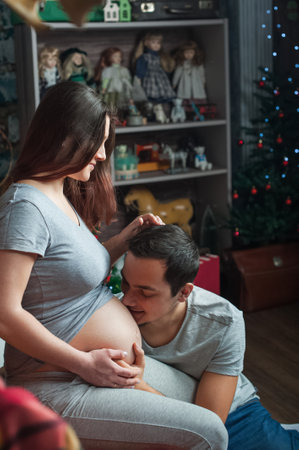 Loving couple in anticipation of baby. Man kisses belly of pregnant woman..の写真素材