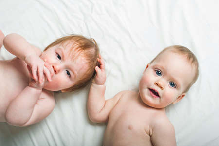 Two little babies in diapers on bed close up and copy space.