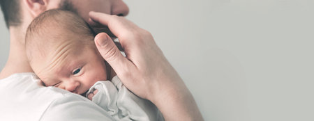 Newborn baby and young dad close up. Baby care concept, newborn weight, diapers, napkins, temperature, bilirubin... Banner.の写真素材
