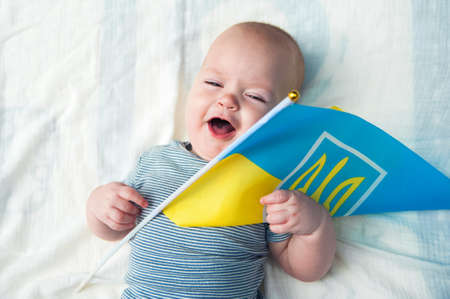 Cute baby 5 months old with flag of Ukraine close-up.