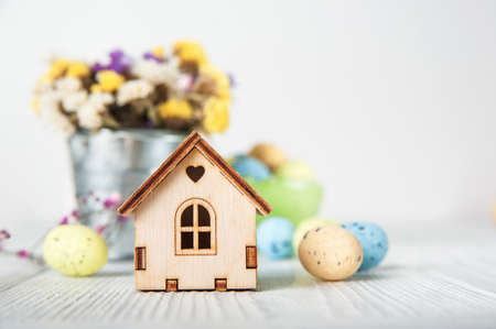 Happy Easter greeting card. Miniature wooden house.Rabbits, colorful eggs, spring flowers with tag...