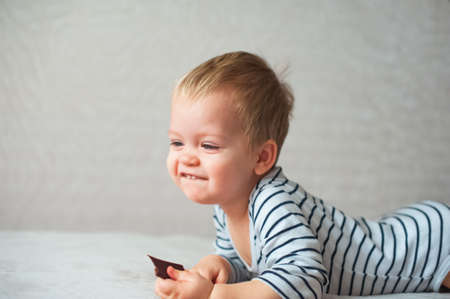 Funny toddler boy playing with candy in hand..