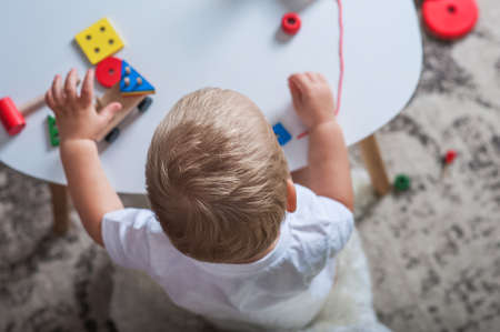 Handsome toddler boy playing with educational wooden and plastic toys in children's room.の写真素材