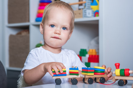 Handsome toddler boy playing with educational wooden and plastic toys in children's room.の写真素材