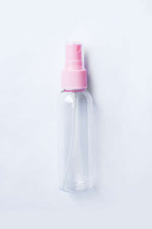 Empty plastic cosmetic bottle with pink cap on white background close-up.