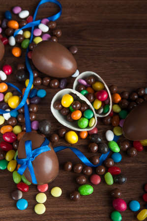 Happy Easter greeting card. composition with delicious sweets, chocolate eggs and blue bow on wooden...