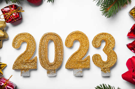 Happy New Year 2023 greeting card. Candle numbers on white background and layout of Christmas tree, balls, gifts. Close up and copy space, Selective focus..の写真素材