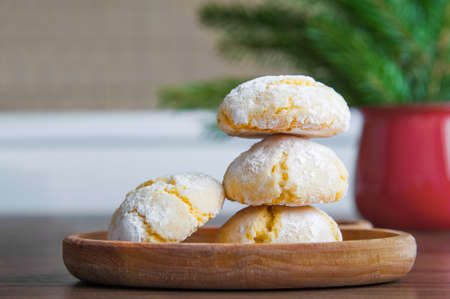 Orange cookies in powdered sugar on table with Christmas tree and cup..の写真素材