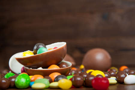 Happy Easter greeting card. composition with delicious sweets, chocolate eggs on wooden background, space for text.の写真素材