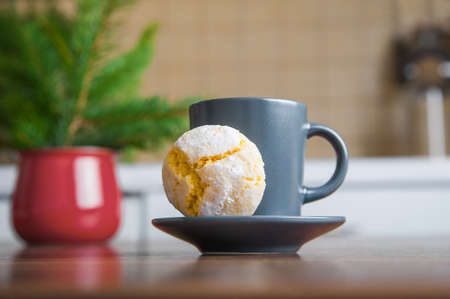 Orange cookies in powdered sugar on table with Christmas tree and cup.