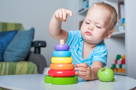 Handsome toddler boy playing with educational wooden and plastic toys in children's room.の写真素材