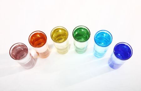 Rainbow shot glasses arranged in a colorful, curving arch.の写真素材
