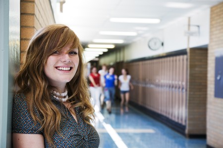A happy high school student with other students running in the school hallway.の写真素材