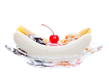 A scrumptious banana split, topped with caramel, strawberry, and chocolate, with a cherry garnish.  Shot on white background.の写真素材