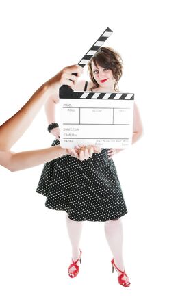 A clapper board being held up in front of a young actress dressed in pinup fashion.  Shot on white background.  Focus on actress.の写真素材