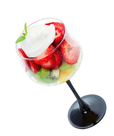 Fresh strawberries, kiwi, & pineapple, topped with whipped cream and a sprig of fresh mint, and served in an elegant wine goblet.  Shot on white background.の写真素材