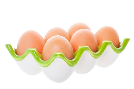 Half a dozen brown eggs in a green ceramic egg tray.  Shot on white background.の写真素材