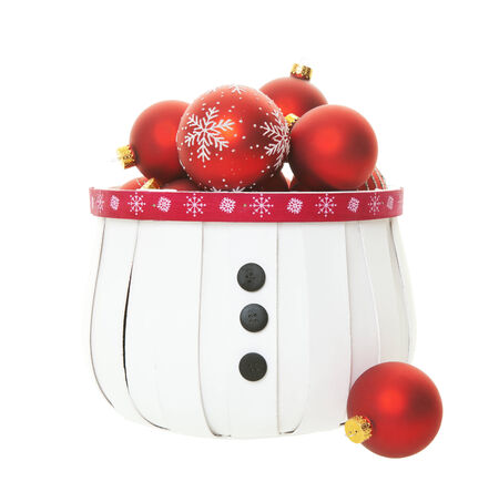 A snowman inspired basket bulging with a multitude of red Christmas balls on white background.の写真素材
