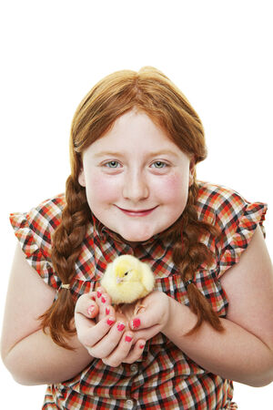 A 10 year old farm girl holding a fluffy, newborn chick on white background の写真素材