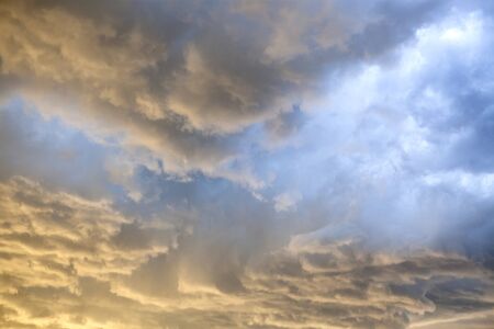 Tumultuous  storm clouds lit up by the setting sun.