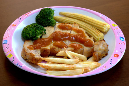 A lovely dish of the pork steak topped with the potato sauce served with french fried and vegetables.の写真素材