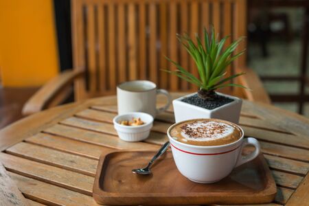 Hot capuchino Coffee in white cup on wooden tableの写真素材