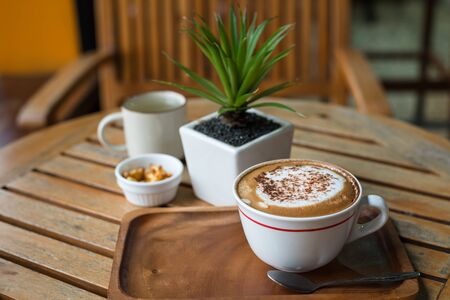 Hot capuchino Coffee in white cup on wooden tableの写真素材