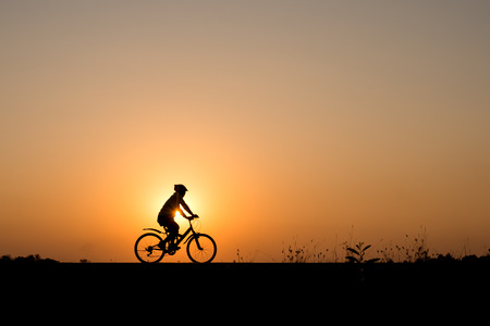 Silhouette of cyclist in motion on the background of beautiful sunsetの写真素材