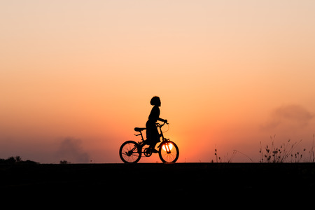 Silhouette of cyclist in motion on the background of beautiful sunsetの写真素材