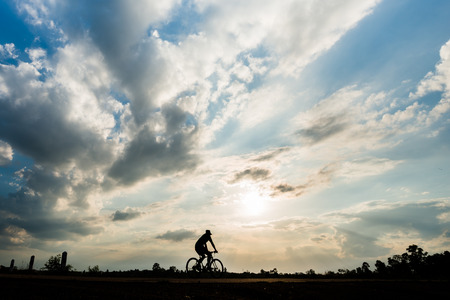 Silhouette of cyclist with friend in motion on the background of beautiful sunsetの写真素材