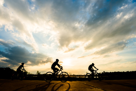 Silhouette of cyclist with friend in motion on the background of beautiful sunsetの写真素材