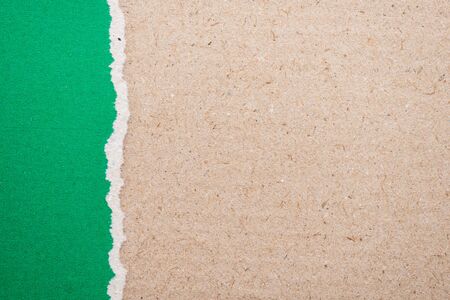 Teared, ripped green paper on brown backgroundの写真素材