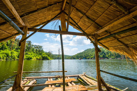 Bamboo raft floating in lake with mountain backgroundの写真素材