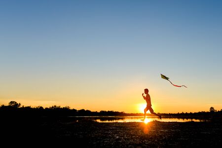 silhouette of children flying a kite at sunset invoke childhood memories