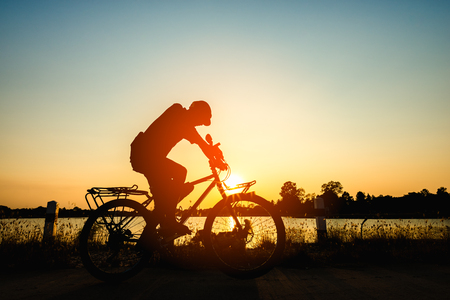 Silhouette of cyclist in motion on the background of beautiful sunsetの写真素材