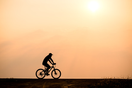 Silhouette of cyclist in motion on the background of beautiful sunsetの写真素材