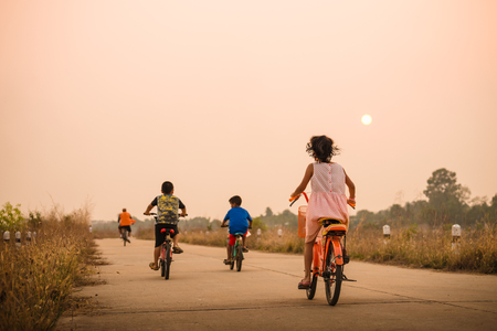 boy and girl cycling in motion on the background of beautiful sunsetの写真素材